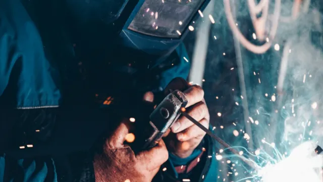 Fotografia de um soldador fazendo a solda de um equipamento